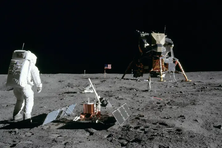 Buzz Aldrin beside the seismometer he has just deployed, with the flag and Eagle beyond, photographed by Armstrong, 20 July 1969