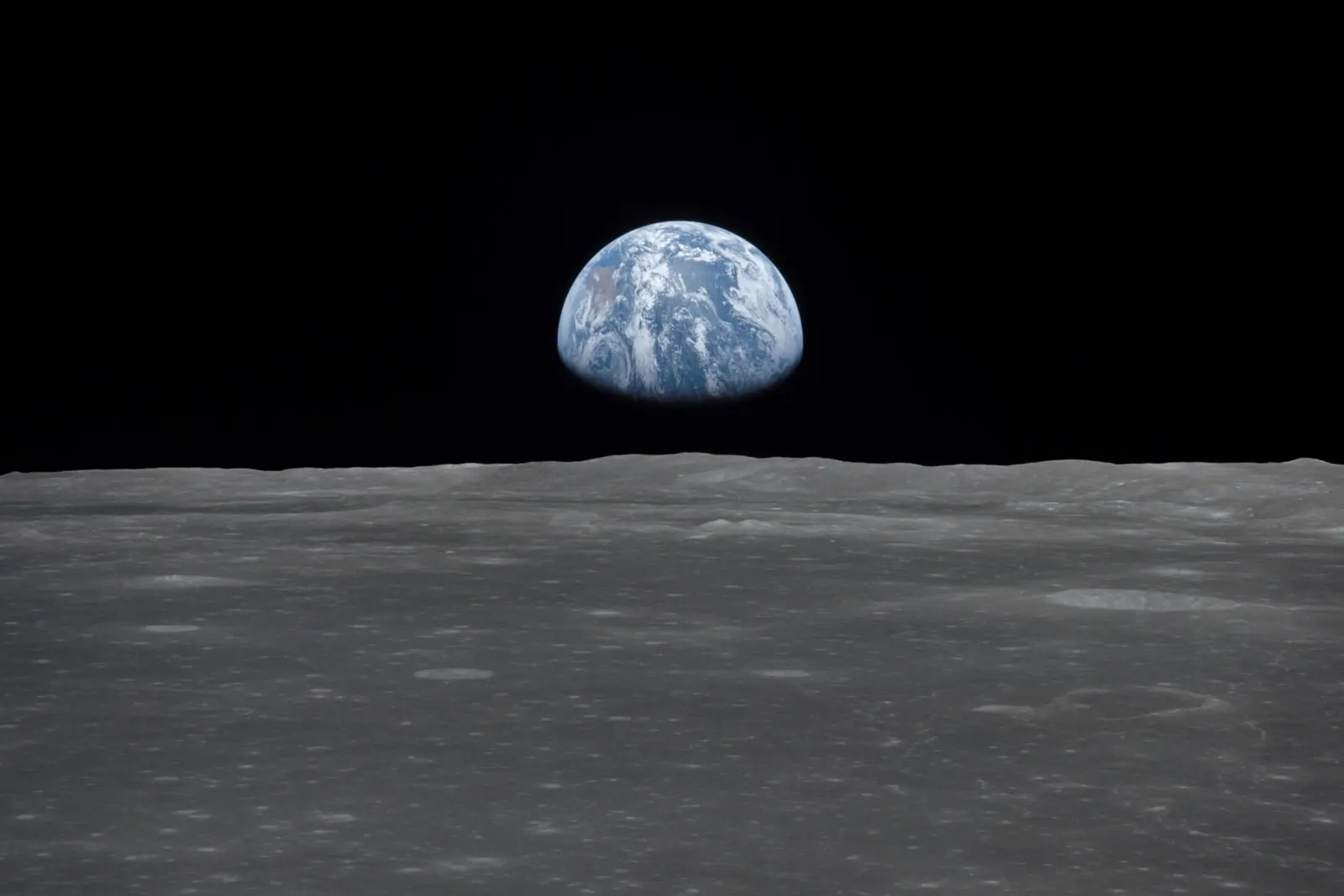 Earth rises over the lunar horizon near Smyth's Sea, photographed from Apollo 11 in lunar orbit, July 1969