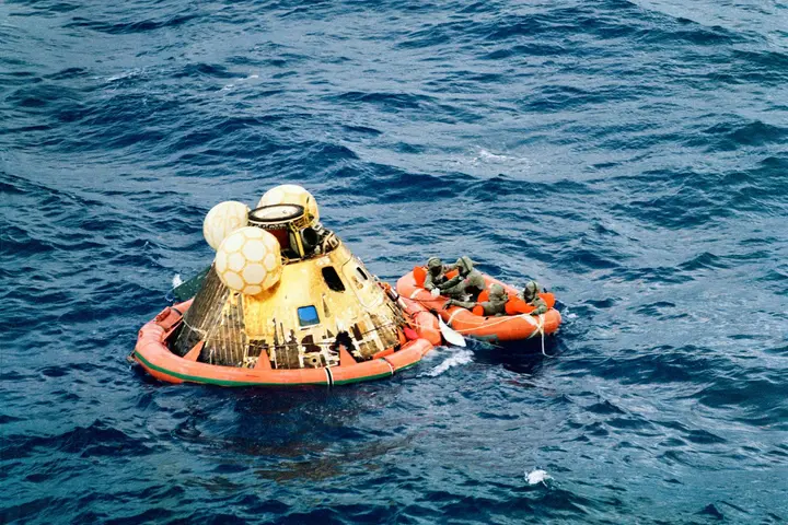 Columbia rides the Pacific after splashdown as the crew and a Navy frogman wait in a raft for pickup by USS Hornet, 24 July 1969