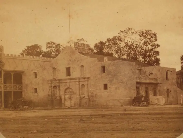 The Alamo church in the late 1870s, when the long barrack beside it was a store. Half of a Doerr & Jacobson stereoview.
