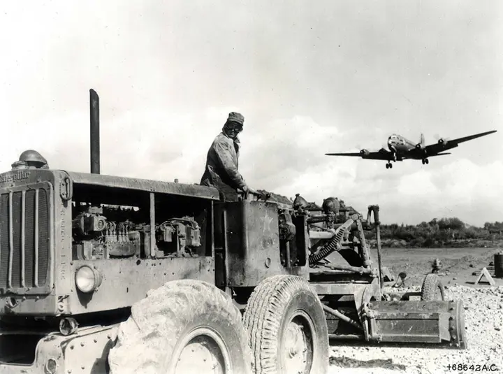 Pvt. William Moore of the 759th Engineers grades a new 5,500-foot runway at Tempelhof as a C-54 comes in to land.