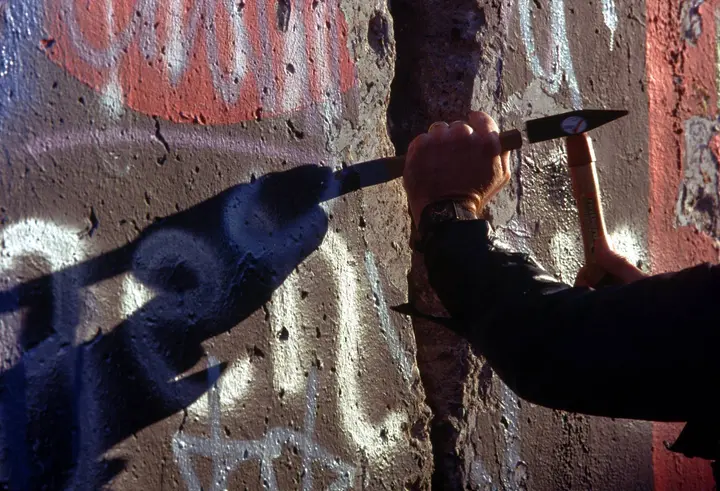 A West Berliner takes a hammer and chisel to the Wall for a souvenir, November 1989