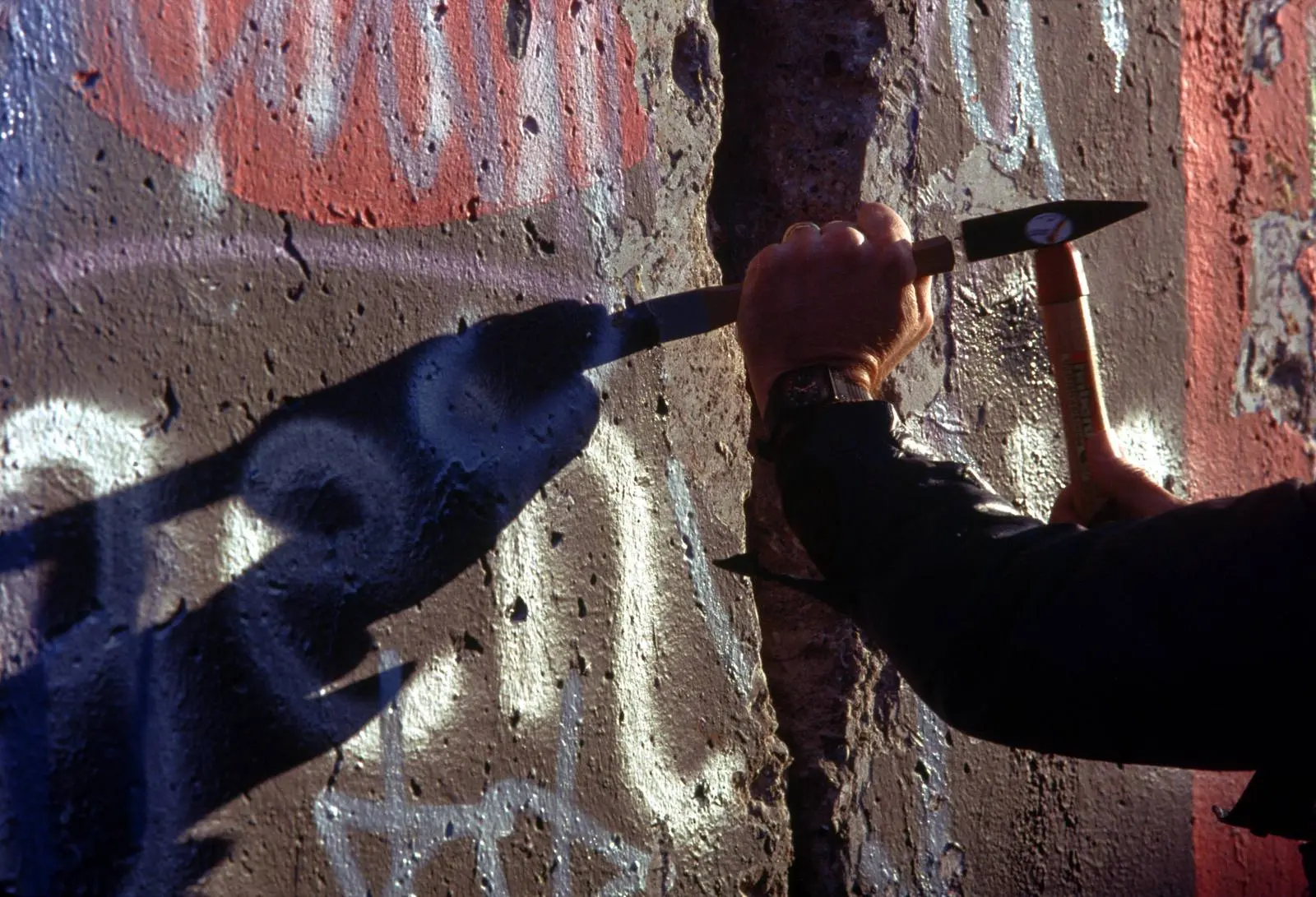 A West Berliner takes a hammer and chisel to the Wall for a souvenir, November 1989