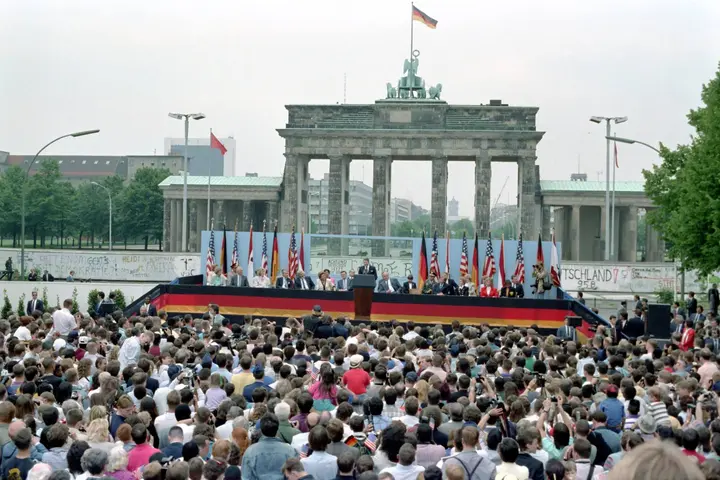 President Reagan speaks to the crowd at the Brandenburg Gate, West Berlin, 12 June 1987. The Wall runs behind the stage