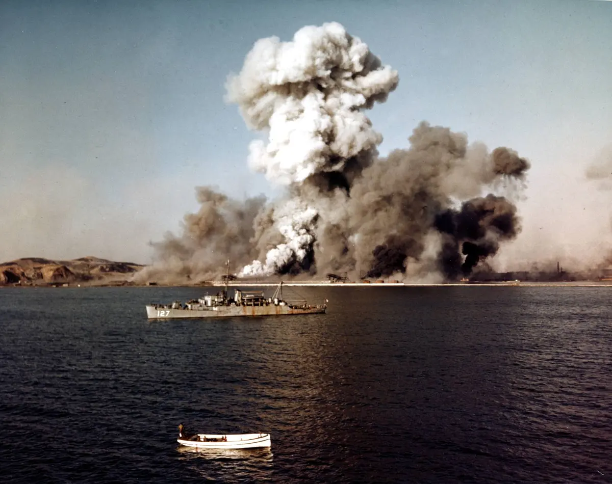 Demolition charges level the port of Hungnam as the high-speed transport USS Begor stands by for the last boats out, 24 December 1950 (80-G-K-11771)