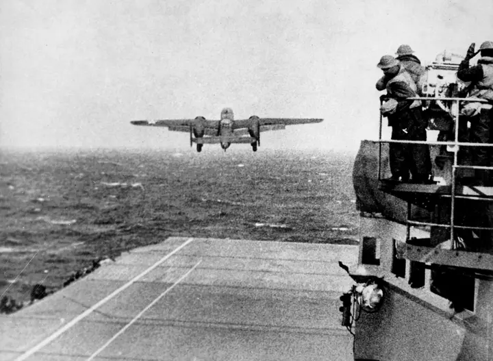 A B-25B clears the bow of USS Hornet at the start of the Doolittle Raid, 18 April 1942, as sailors watch from the island (80-G-41196).