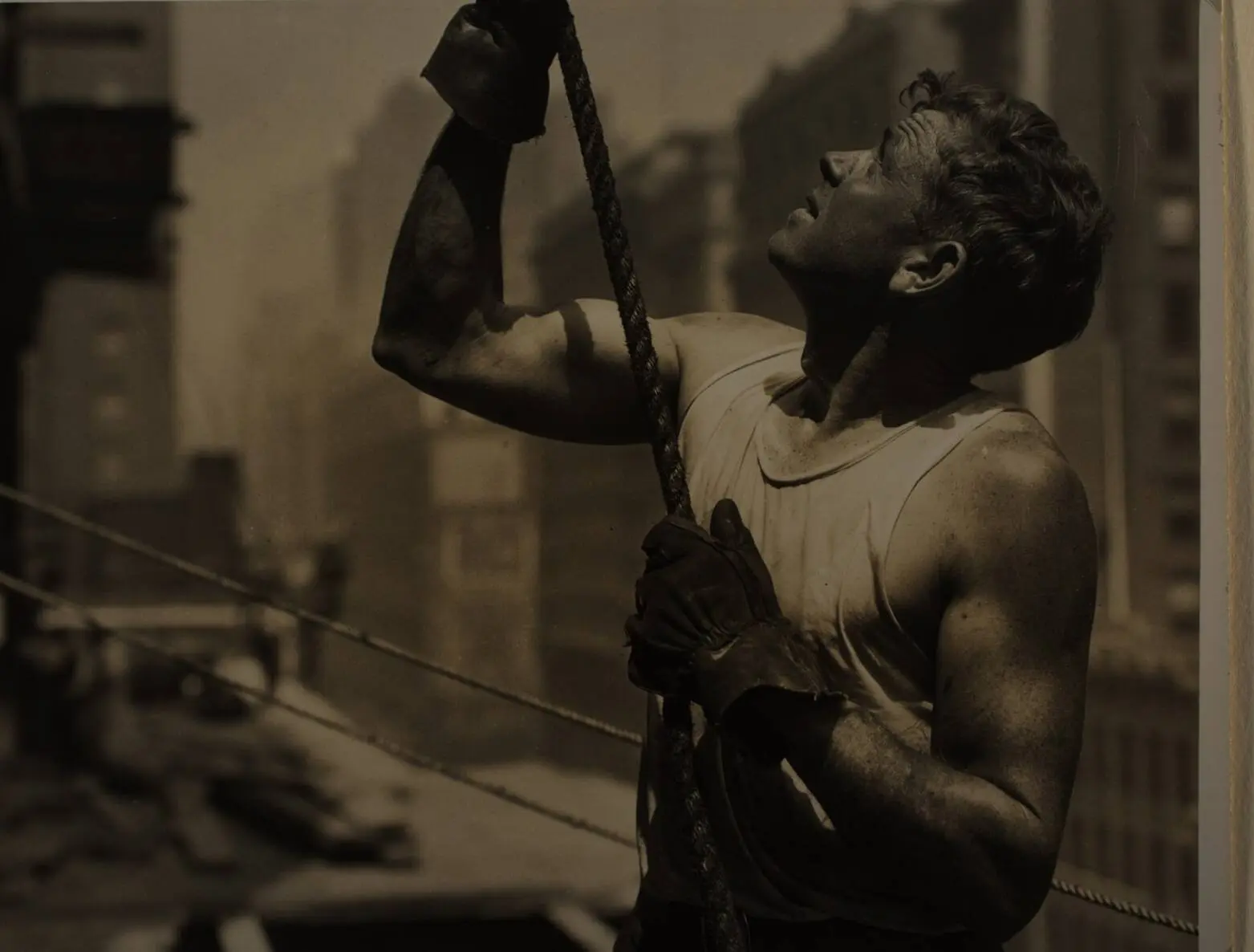 The Hoister: a derrick man hauls on a cable high on the Empire State Building, about 1931.