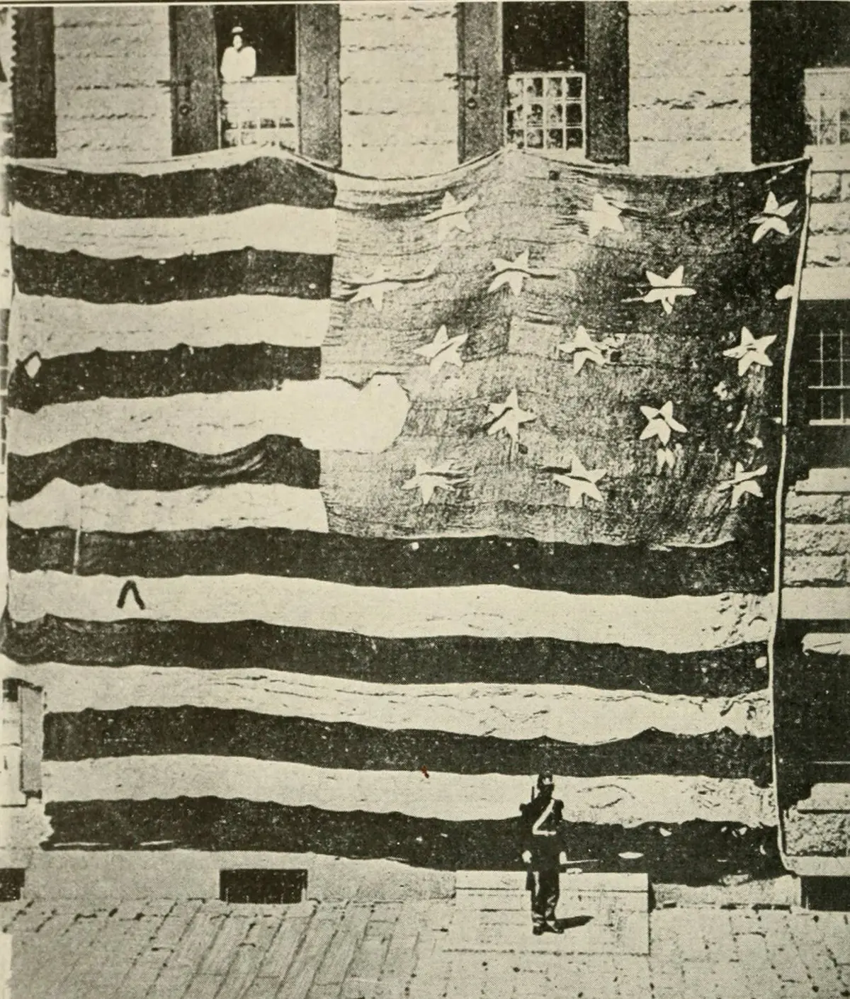 The first known photograph of the Star-Spangled Banner, Boston Navy Yard, 1873. The man at the bottom gives the scale.