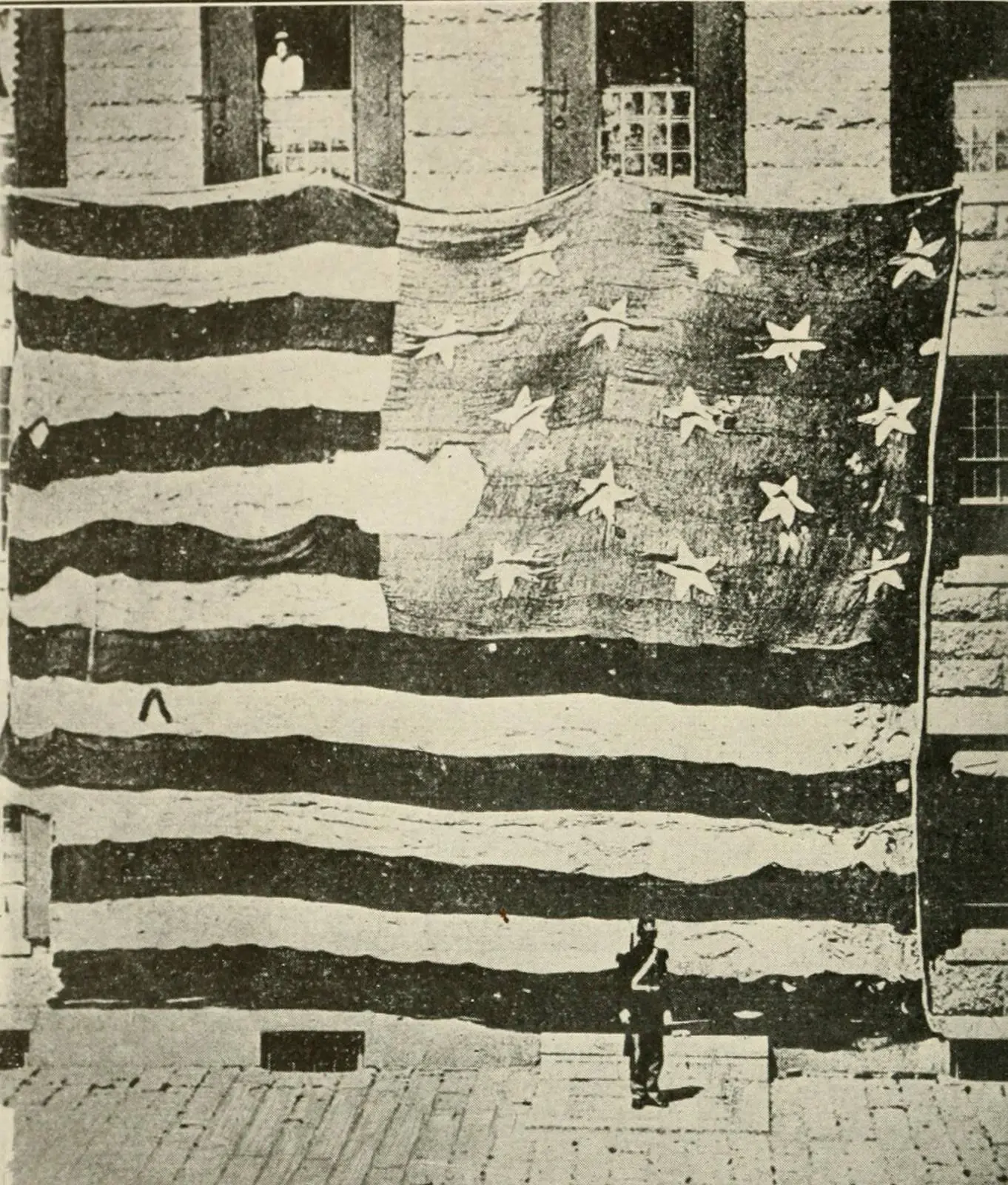 The first known photograph of the Star-Spangled Banner, Boston Navy Yard, 1873. The man at the bottom gives the scale.