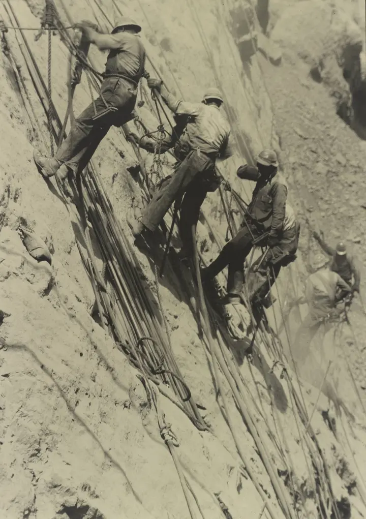 High scalers on ropes and bosun's chairs work the wall of Black Canyon, photographed by Ben Glaha, c. 1934