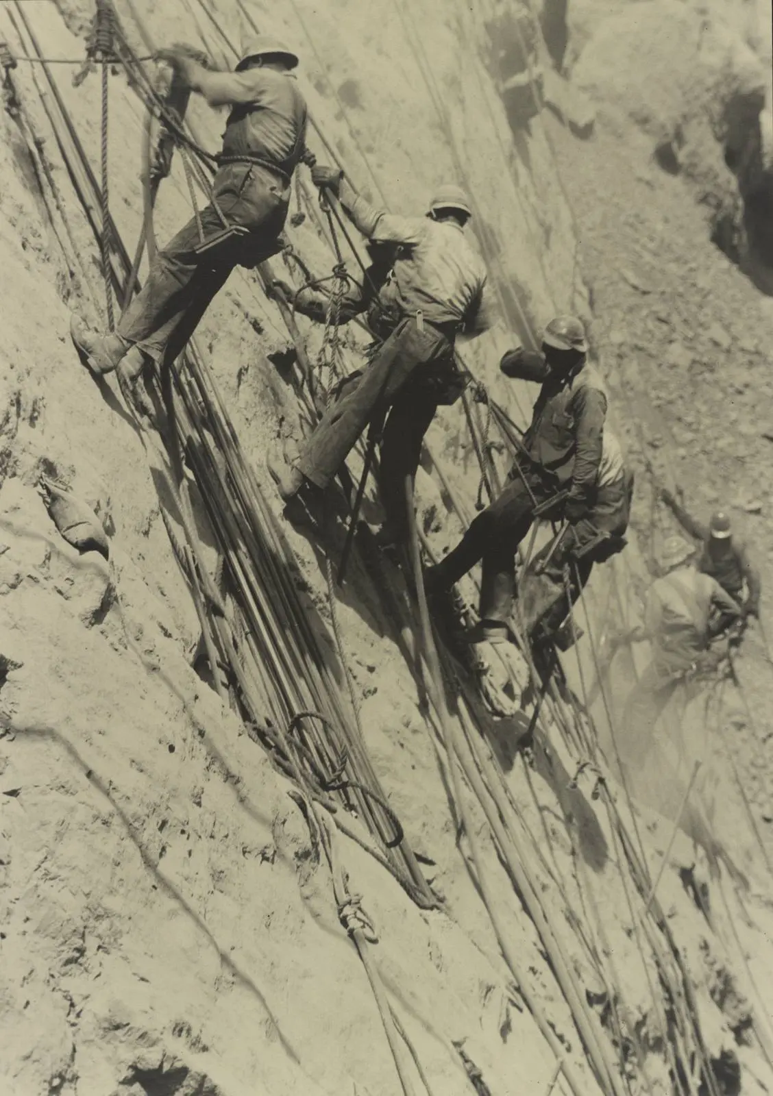 High scalers on ropes and bosun's chairs work the wall of Black Canyon, photographed by Ben Glaha, c. 1934