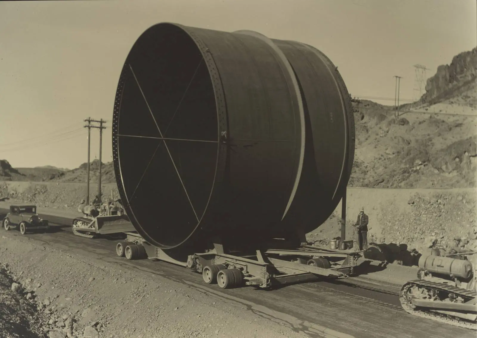A 30-foot-diameter steel penstock section hauled to the dam on a special trailer, photographed by Ben Glaha, c. 1934