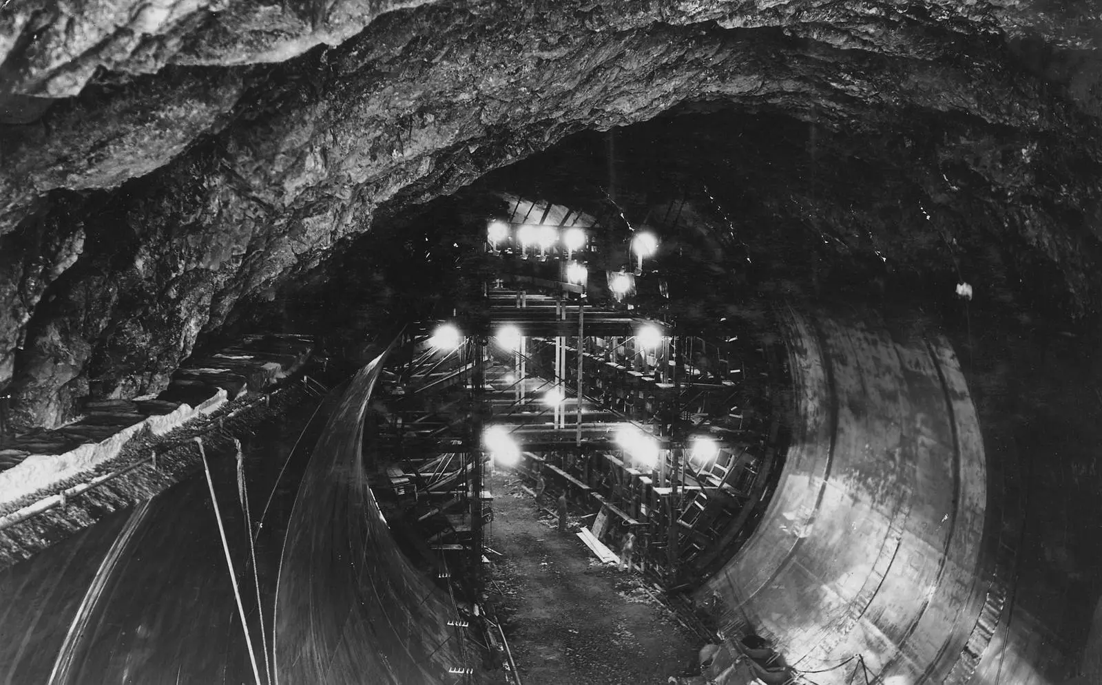 Concrete crews line Diversion Tunnel No. 2 under floodlights, a truck parked on the tunnel floor, May 10, 1932