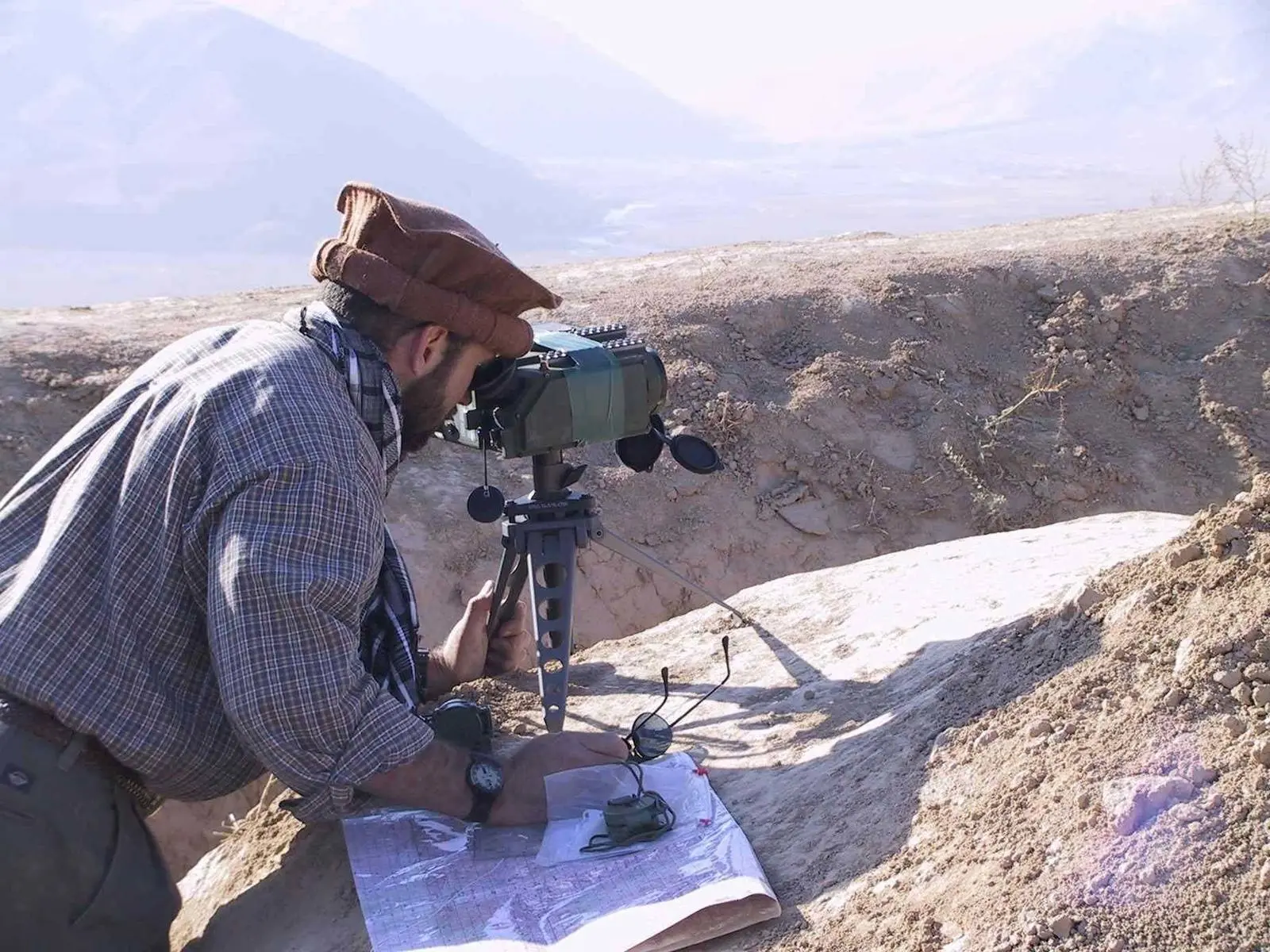 A Special Forces captain in local dress aims a portable laser designator to guide Air Force and Navy bombs onto Taliban lines, Afghanistan, 2001
