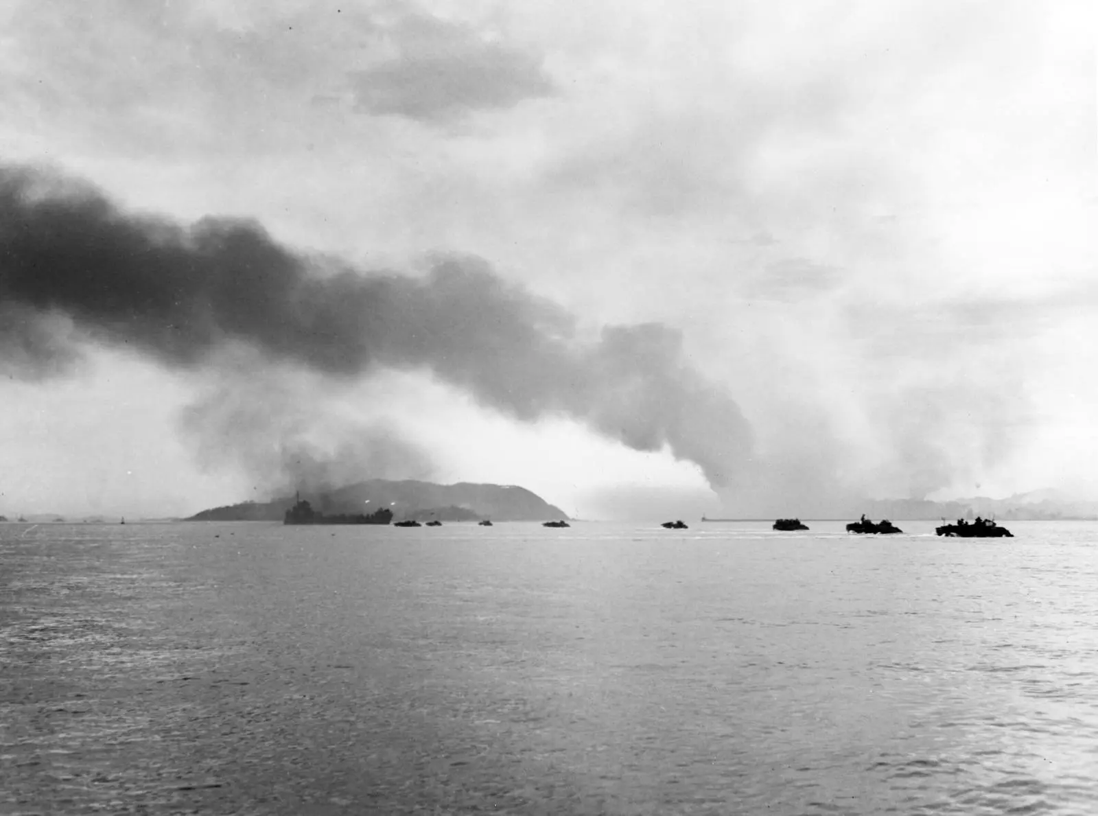 A rocket ship fires as amphibian tractors cross the line of departure for Blue Beach, with Wolmi-do and the burning waterfront beyond, 15 September 1950 (80-G-420024).