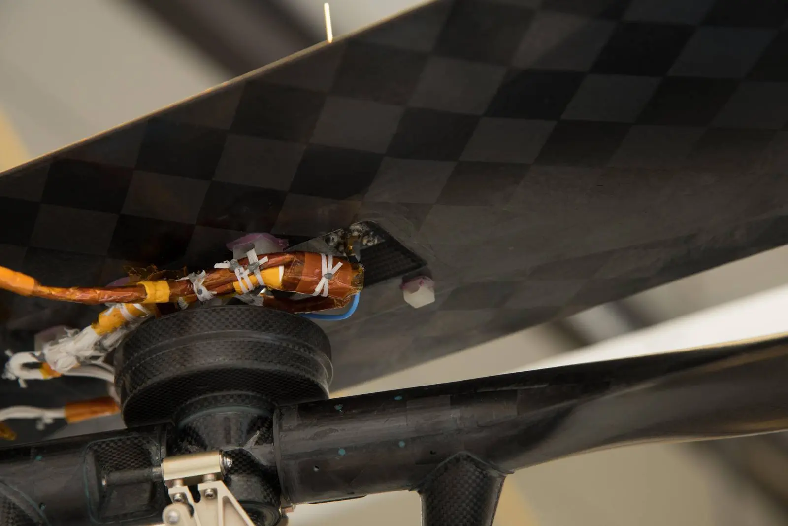 A swatch of muslin from the 1903 Wright Flyer's lower-left wing, wrapped around a cable beneath Ingenuity's solar panel