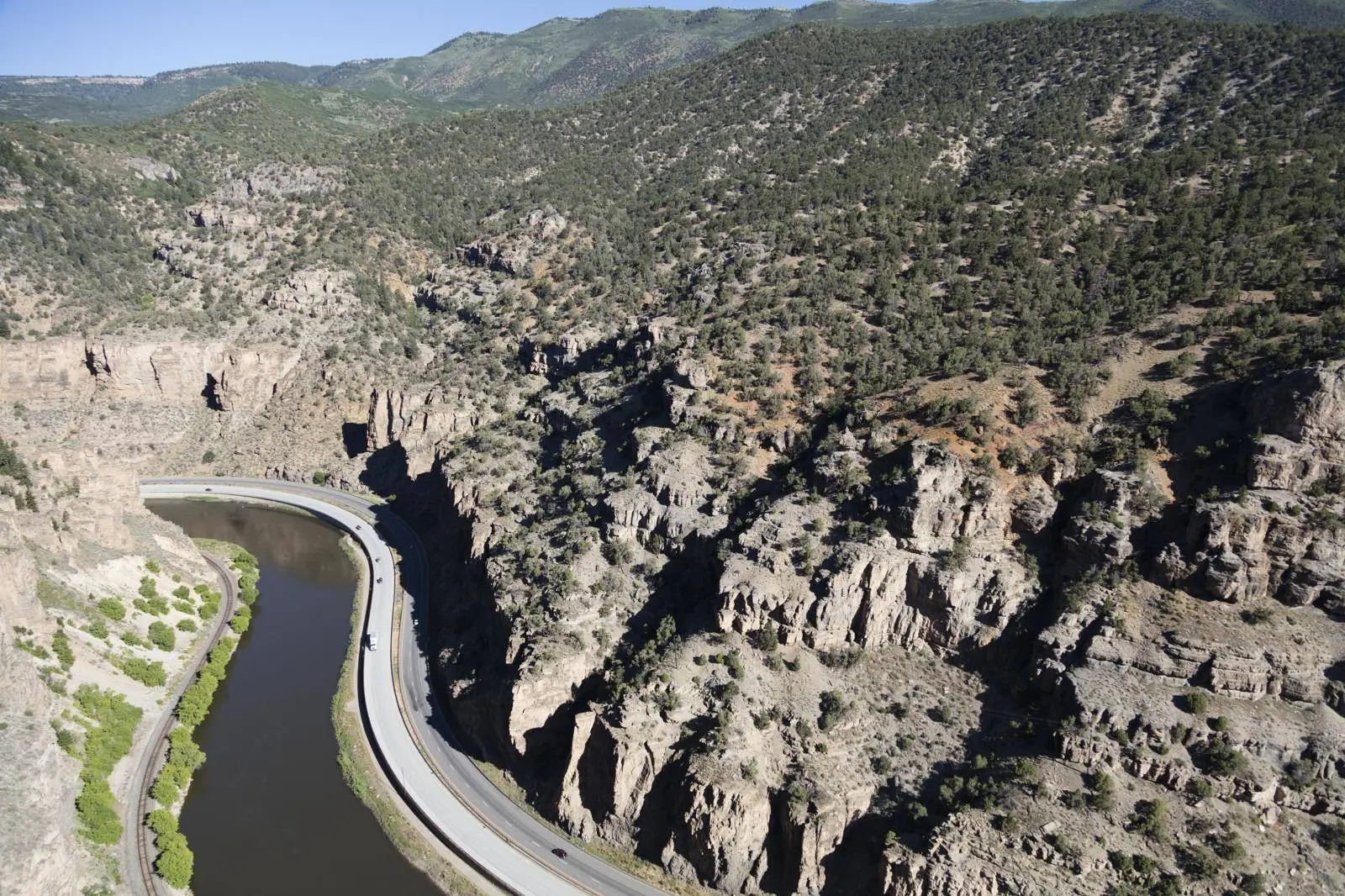 I-70 follows a bend of the Colorado River beneath the cliffs of Glenwood Canyon, Colorado. Aerial photograph, 2016.