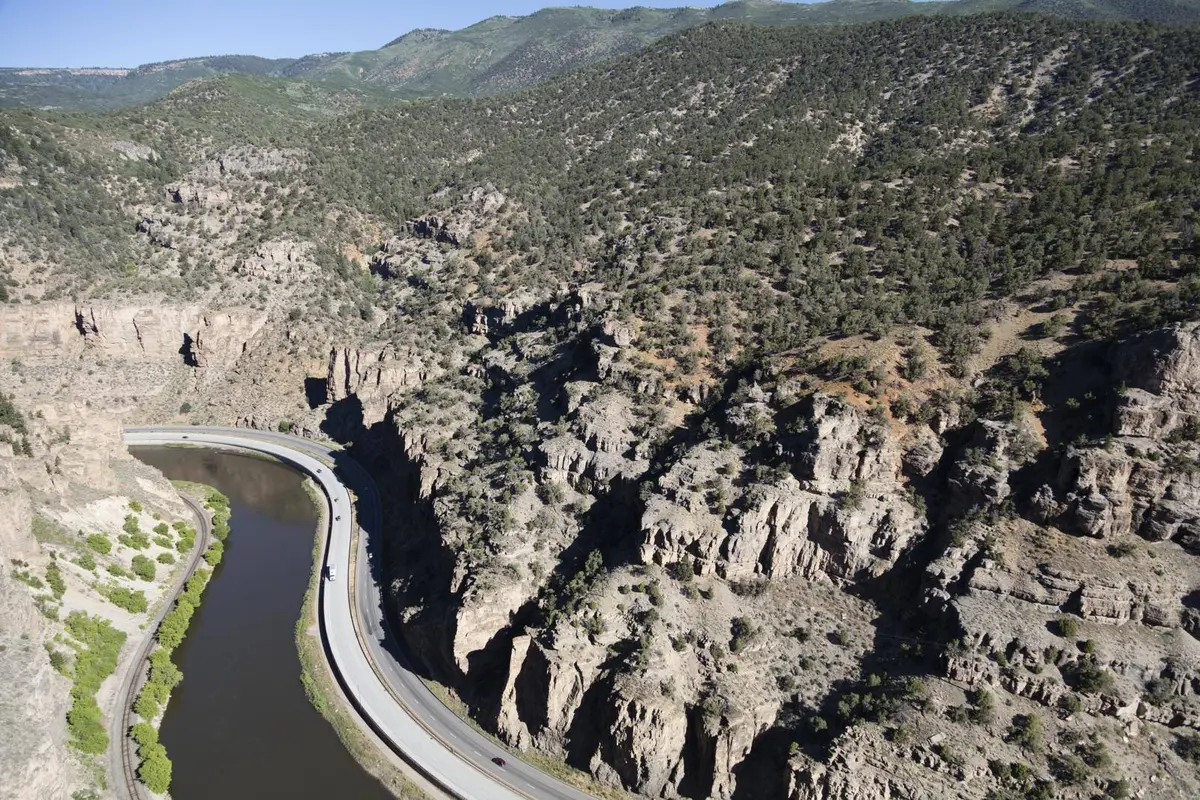 I-70 follows a bend of the Colorado River beneath the cliffs of Glenwood Canyon, Colorado. Aerial photograph, 2016.
