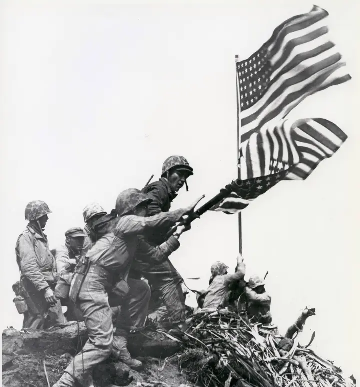 Marines raise the larger second flag as the first comes down atop Mount Suribachi, 23 February 1945