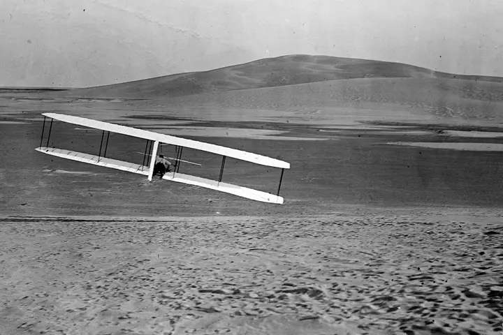 Wilbur Wright banks the 1902 glider into a right turn while gliding from No. 2 Hill, Kill Devil Hills, N.C., October 24, 1902