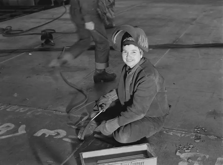 A “Wendy the Welder” pushes back her helmet during a pause in her work at the Richmond shipyards, February 1943.
