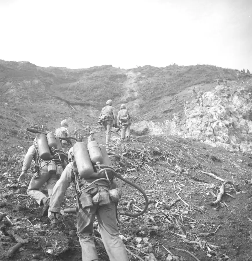 Marines carrying flamethrowers climb the slopes of Mount Suribachi, February 1945