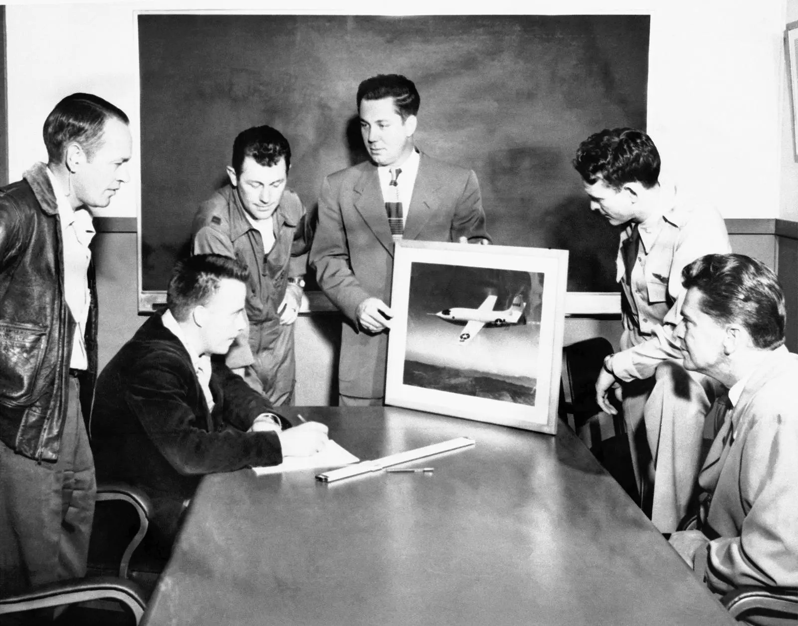 Yeager, Ridley and the NACA Muroc team study Bob Hoover's photo of the X-1 in supersonic flight, 1948.
