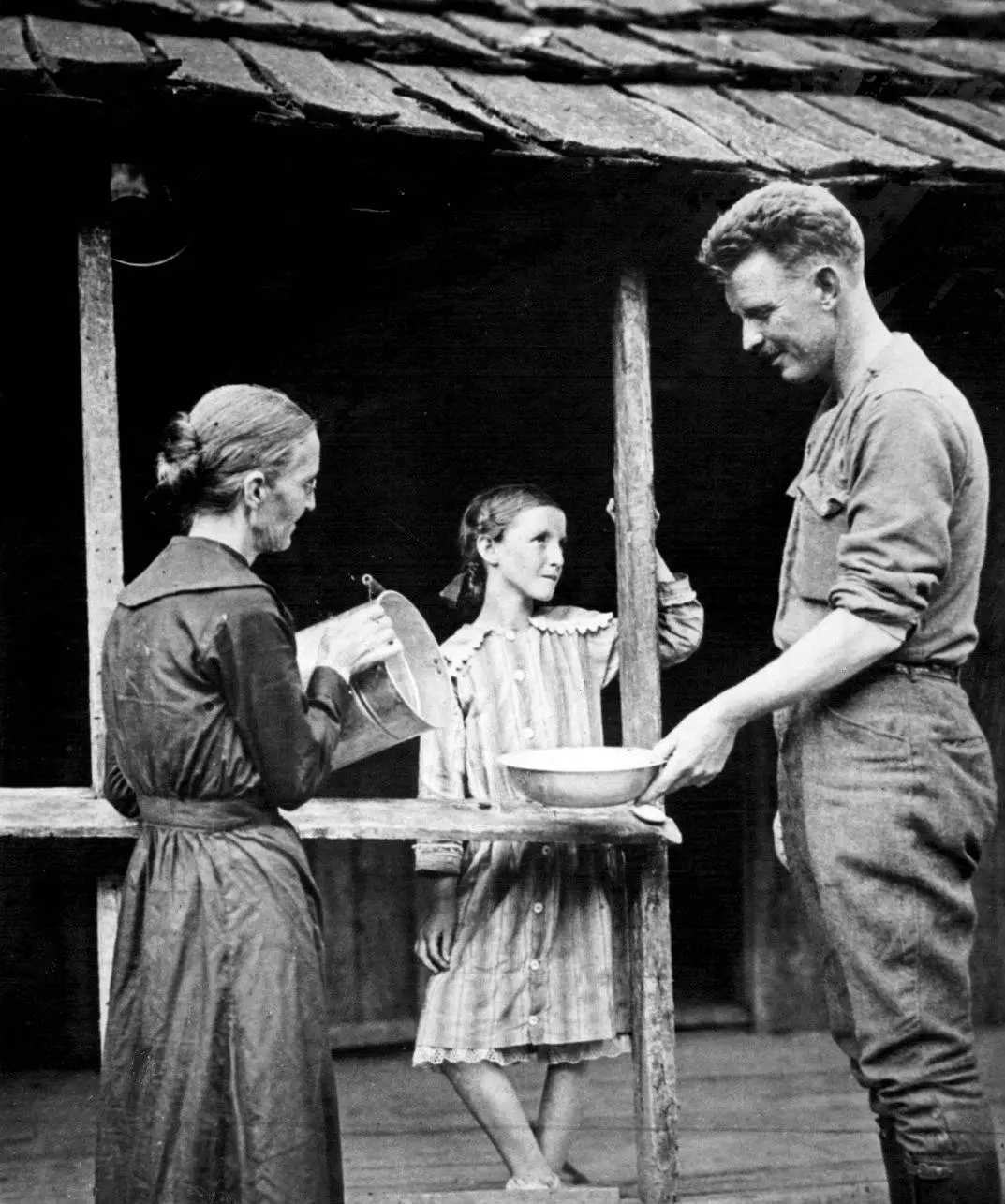 Home in Pall Mall, York washes up at the family cabin while his mother pours and his sister looks on, 1919