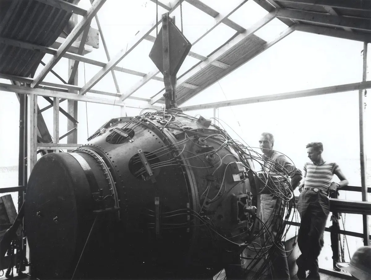 The Gadget in the shed atop the 100-foot Trinity tower, with Norris Bradbury (left) and Boyce McDaniel, July 1945.