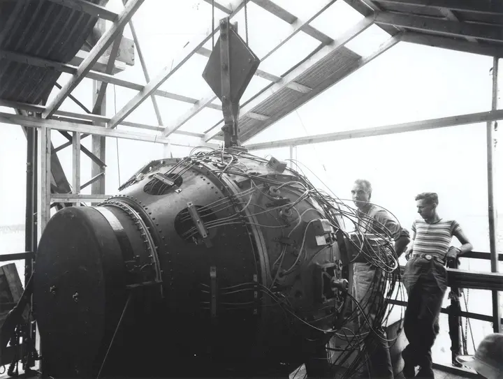 The Gadget in the shed atop the 100-foot Trinity tower, with Norris Bradbury (left) and Boyce McDaniel, July 1945.