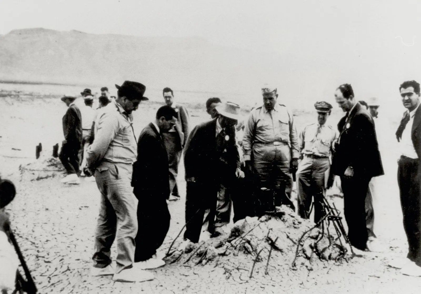 Oppenheimer (light hat) and Groves (in uniform) at the rubble of the Trinity tower at ground zero, September 1945.