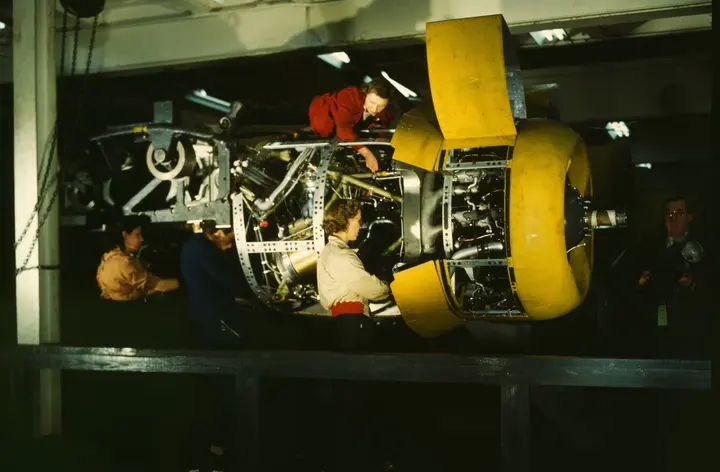 Installing one of the four engines on a plane at Willow Run, photographed in color by Howard Hollem