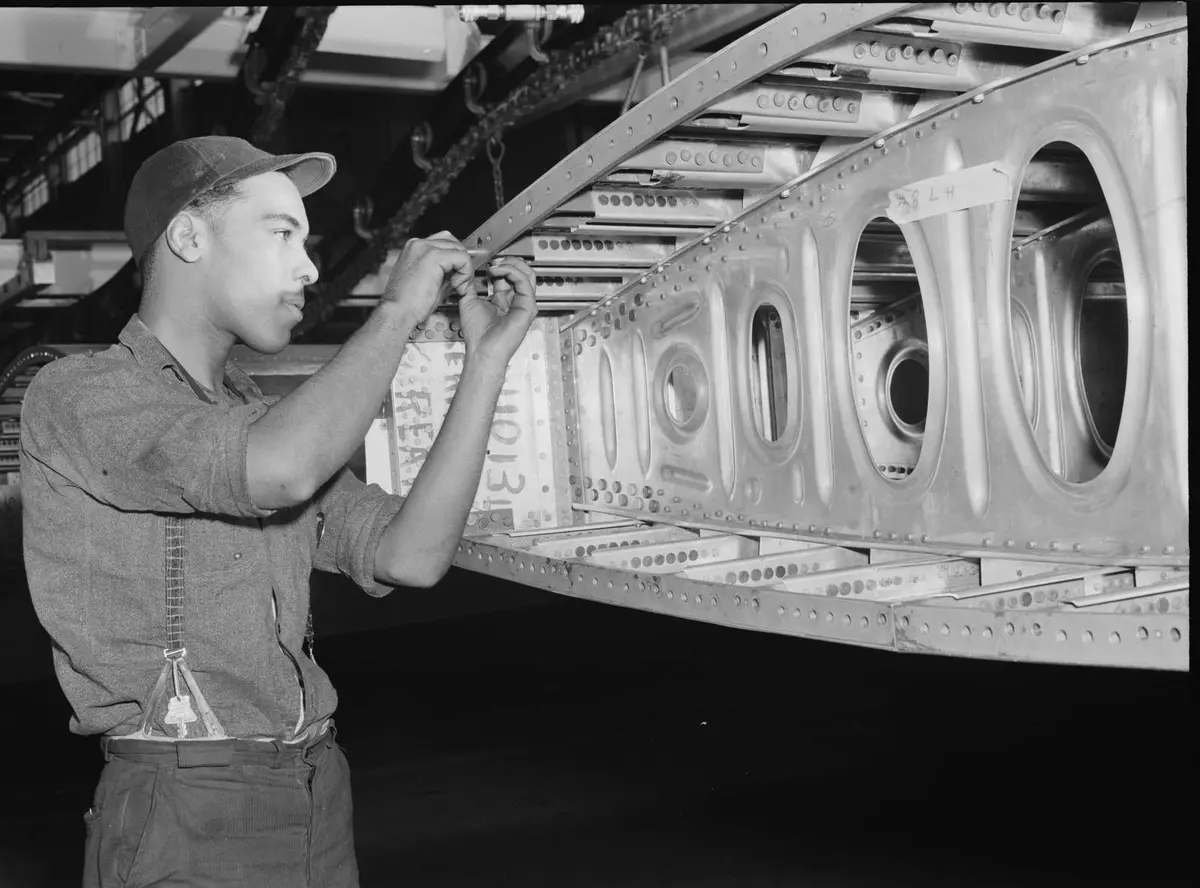 A Willow Run worker installs screws in one end of a bomber wing segment, July 1942